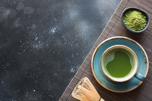 Organic green matcha tea on black table. Top view. Space for text.