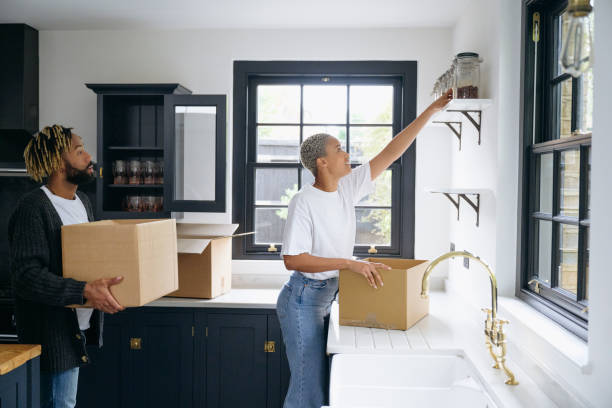 Organized couple unpacking boxes in kitchen on moving day stock photo