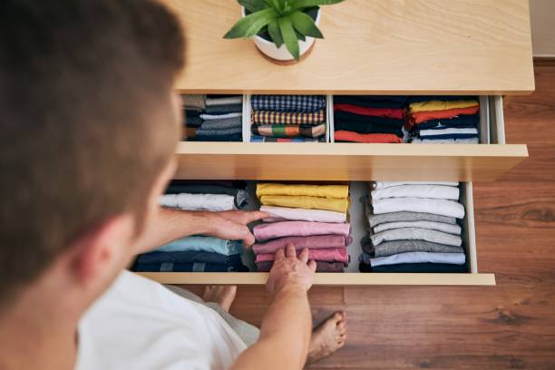 Organizing and cleaning home Organizing and cleaning home. Man preparing orderly folded t-shirts in drawer. arranging stock pictures, royalty-free photos & images