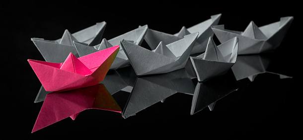 Origami paper ship with sailboats, leadership, marketing concept, social media influencers, HR recruiter, disruptive innovation, standing out concept.