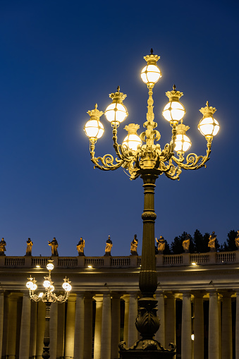 Retro style lamppost night illumination, ornate lamp on the St Peter Square in Vatican, Rome, Italy.