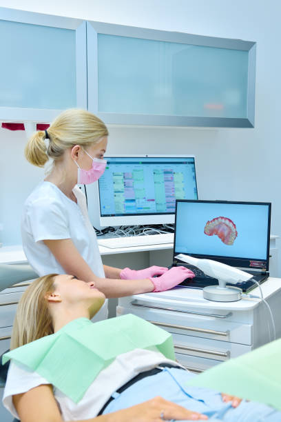 Orthodontist and patient are watching result of a 3D scan on a laptop screen. stock photo