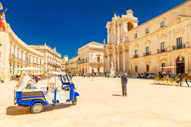 Ortygia, Italy: View of The Cathedral of Syracuse and the central square (Piazza Duomo) with walking people stock photo