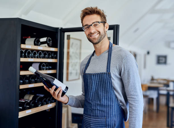Our customers love this one Shot of a handsome young man choosing a bottle of wine in a restaurant camiseta barata stock pictures, royalty-free photos & images