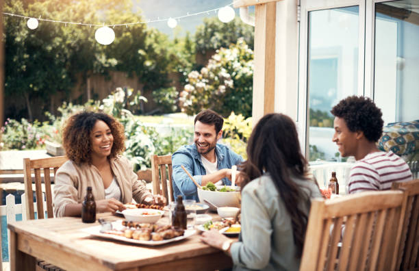 Our love for food is a common thread Shot of a group of friends having a meal together outdoors patio stock pictures, royalty-free photos & images