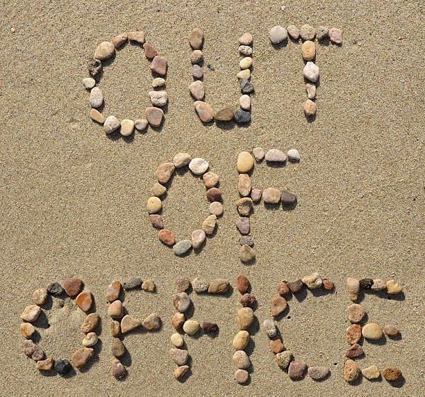 Out of office text written on the beach sand stock photo