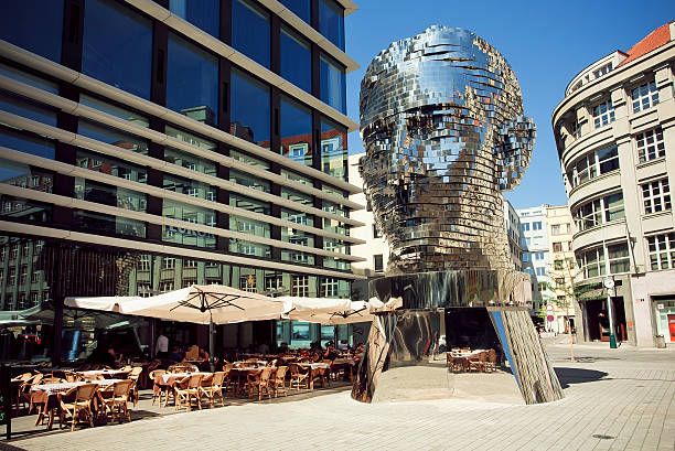 Outdoor cafe near famous artist David Cerny's sculpture Metalmorphosis Prague, Czechia - August 29, 2015: Outdoor cafe near  famous artist David Cerny's sculpture Metalmorphosis in giant head form on August 29, 2015. In 1992 Old Prague was listed in UNESCO Heritage Register prague art stock pictures, royalty-free photos & images