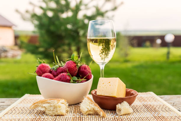 Outdoor spring picnic with strawberry, cheese, bread and glass of wine. stock photo