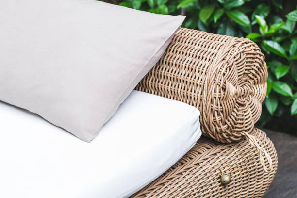 Outdoor wicker bed with white mattress and grey pillow. Clean place for relax and pleasure in hotel garden near pool stock photo
