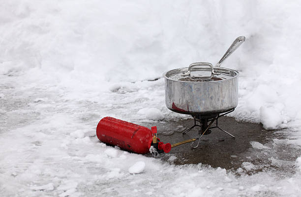 Outdoor winter cooking - surviving a blackout with backpacking stove Stainless steel pot sitting on small backpacking gas stove, surrounded by snow. camping stove stock pictures, royalty-free photos & images