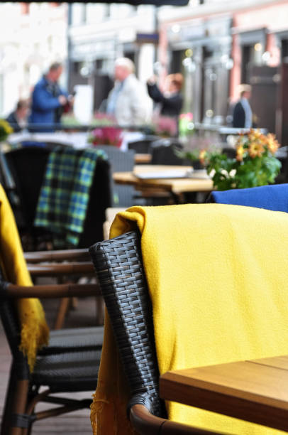 outside patio of an european restaurant - tables and black- brown chairs with yellow blankets for cold weather stock photo
