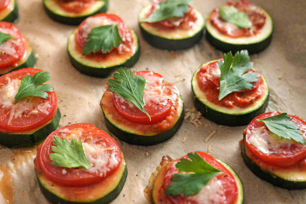 Oven baked zucchini snack with tomato, cheese and parsley garnish, vegetarian mini pizza for a healthy low carb diet, close up shot stock photo