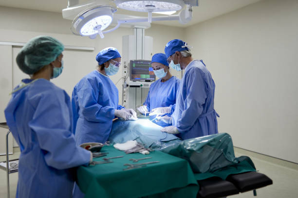 Over the shoulder view of a nurse assisting a team of surgeons. Hospital health care and medicine. general view stock pictures, royalty-free photos & images
