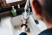 istock Over the shoulder view of senior Asian man filling a glass of filtered water right from the tap in the kitchen at home 1368715188