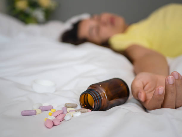 Overdose and suicide concept. Young woman is lying on the bed with a lot of pills. Overdose and suicide concept. xanax pill stock pictures, royalty-free photos & images