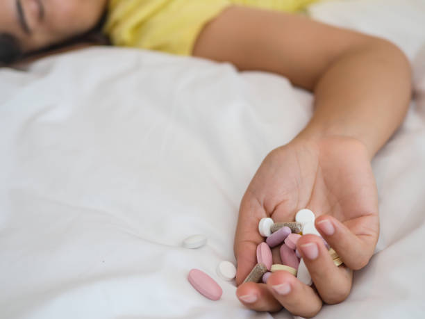Overdose and suicide concept. Young woman is lying on the bed with a lot of pills. Overdose and suicide concept. xanax pill stock pictures, royalty-free photos & images