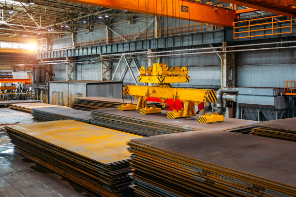 Overhead crane with magnetic grippers lifting steel sheets stock photo