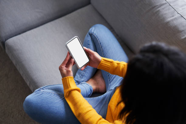 Overhead picture of black woman using smartphone, mobile phone on the sofa stock photo