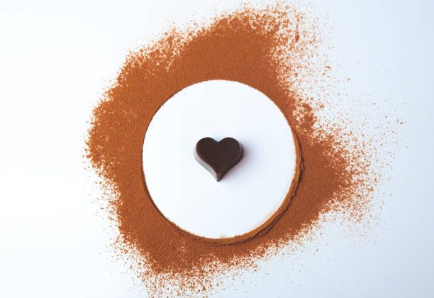 Overhead shot of a heart-shaped chocolate surrounded by cocoa powder. International Chocolate Day. stock photo