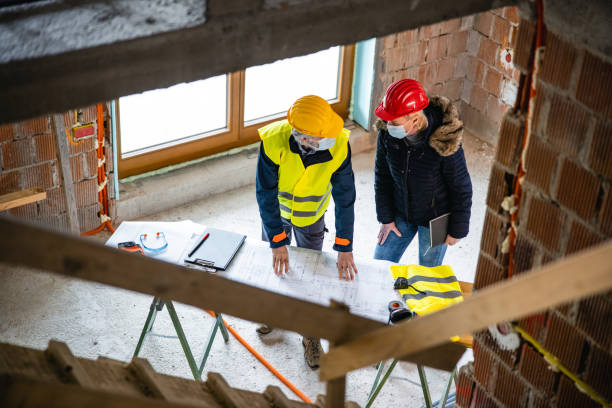 Overhead view of a male construction worker and female client in hard hat discussing building development stock photo