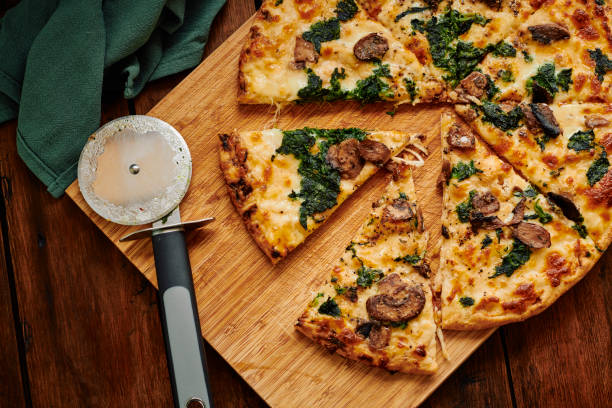 Overhead view of a sliced Spinach and Mushroom pizza. stock photo