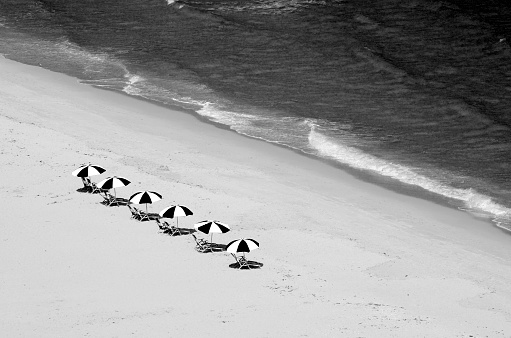 Overhead view of beach chairs and surf of the Atlantic Ocean in West Palm Beach, Florida captured in black and white