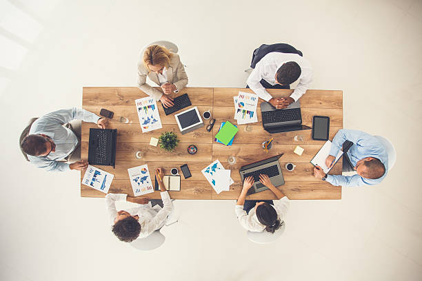 Overhead view of business meeting Overhead view of group of business people sitting at office desk, having a business meeting. conference table stock pictures, royalty-free photos & images