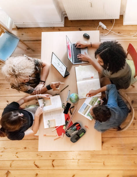 overhead view on four young woman working together on concepts at desk stock photo