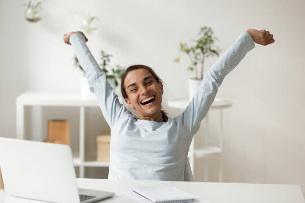 Overjoyed smiling young mixed race lady relaxing after finishing project. Head shot portrait overjoyed smiling young mixed race lady rising hands, stretching back, relaxing after finishing project. Happy millennial woman employee celebrating working day finish at office. happy friday stock pictures, royalty-free photos & images