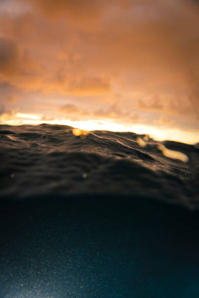 Over-under ocean water surface shot at sunset stock photo