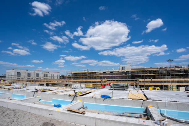 Overview over a building site under a clear sunny blue sky. Reinforced concrete is being constructed with the aid of a crane stock photo