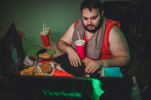 overweight-man-gamer-playing-video-games-on-desktop-computer-picture-id1179570233