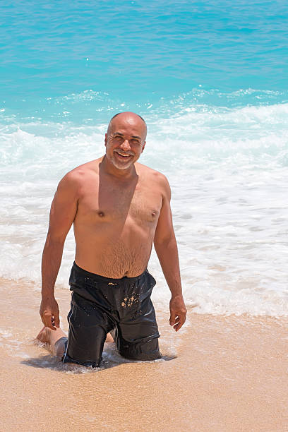overweight senior bald man on the beach - bald beach imagens e fotografias de stock