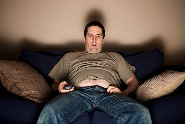 Overweight slob watching TV stock photo