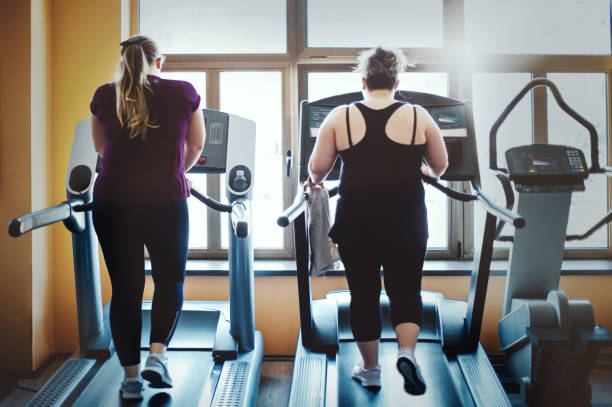 Overweight women running on a treadmill in the gym. stock photo