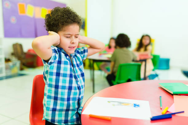 Overwhelmed preschooler with autism in kindergarten stock photo