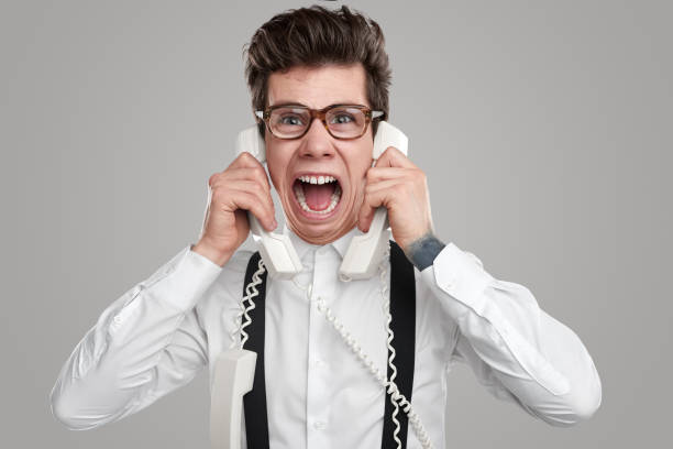 Overworked man screaming during telephone call stock photo