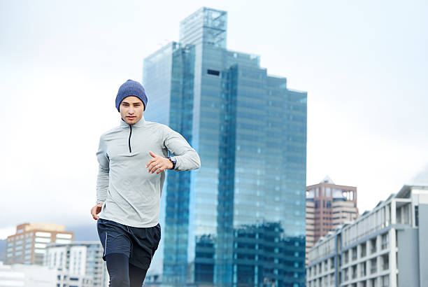 Cropped shot of a young man jogging through the city