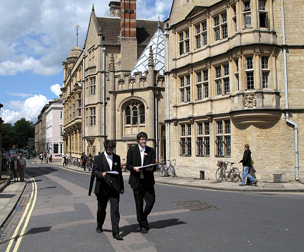 Oxford University "Oxford, England - May 29, 2007:  View of the buildings of Hertford College.  Two students are seen wearing the academic dress of undergraduate commoners, with the carnation signifying that they are writing examinations.  http://en.wikipedia.org/wiki/Academic_dress_of_the_University_of_Oxford#Undergraduates" oxford university stock pictures, royalty-free photos & images