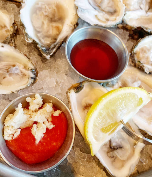Oysters with cocktail sauce and vinegar mignonette High angle view of oysters with a slice of lemon, cocktail sauce and a vinegar mignonette cocktail sauce stock pictures, royalty-free photos & images