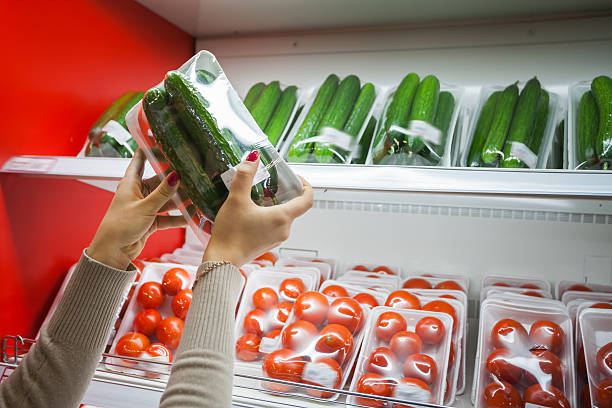 Packaged cucumber with woman hand in the supermarket stock photo