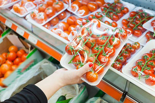 Packaged tomato with woman hand in the supermarket stock photo