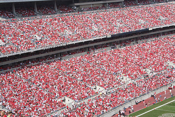 Packed football stadium focused on crowd wearing red stock photo