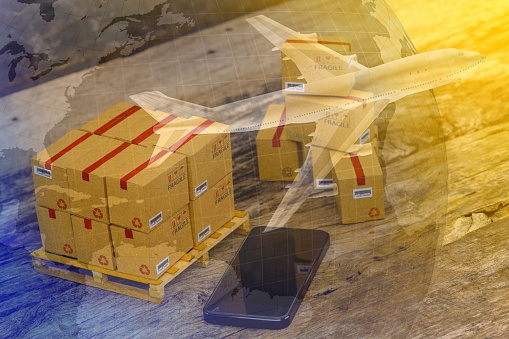 Packing boxes small goods and cell phone with a plane flies above world map. business concept about transportation, global shipping, international freight, overseas trade, regional, services remotely.