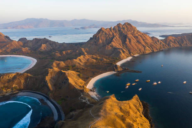 Padar island at sunset with boats anchored in the bay stock photo