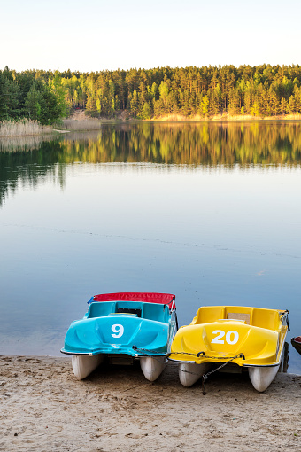 Colorful paddle boats on sandy beach by one of the Blue Lakes, Chernigiv region, Ukraine