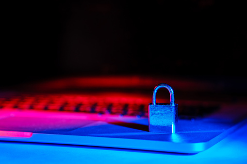 A padlock on a laptop illuminated with blue and red light. Internet security is essential for online shopping and e-commerce. Copy space.