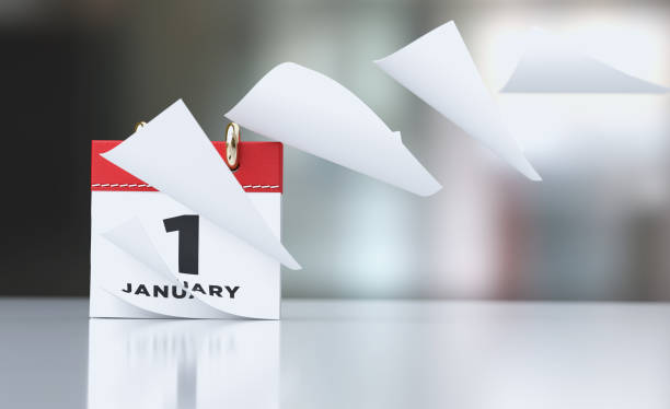 Pages Of A Red Calendar Standing Over Defocused Background Are Flying Away Pages of a red calendar standing over defocused background are flying away. January 1st writes on the calendar. Horizontal composition with copy space. Calendar and reminder concept with selective focus. new years day stock pictures, royalty-free photos & images