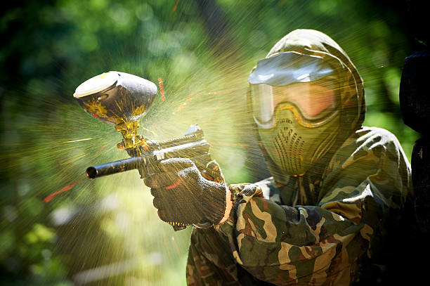 Paintball player with paint ball exploding on his gun stock photo