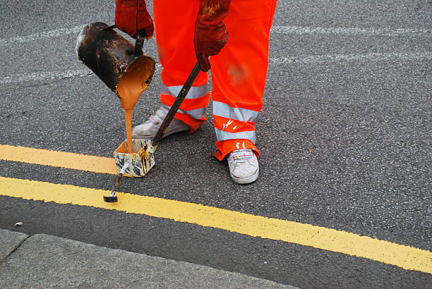 Painter Worker painting double yellow line on the street dividing line road marking stock pictures, royalty-free photos & images